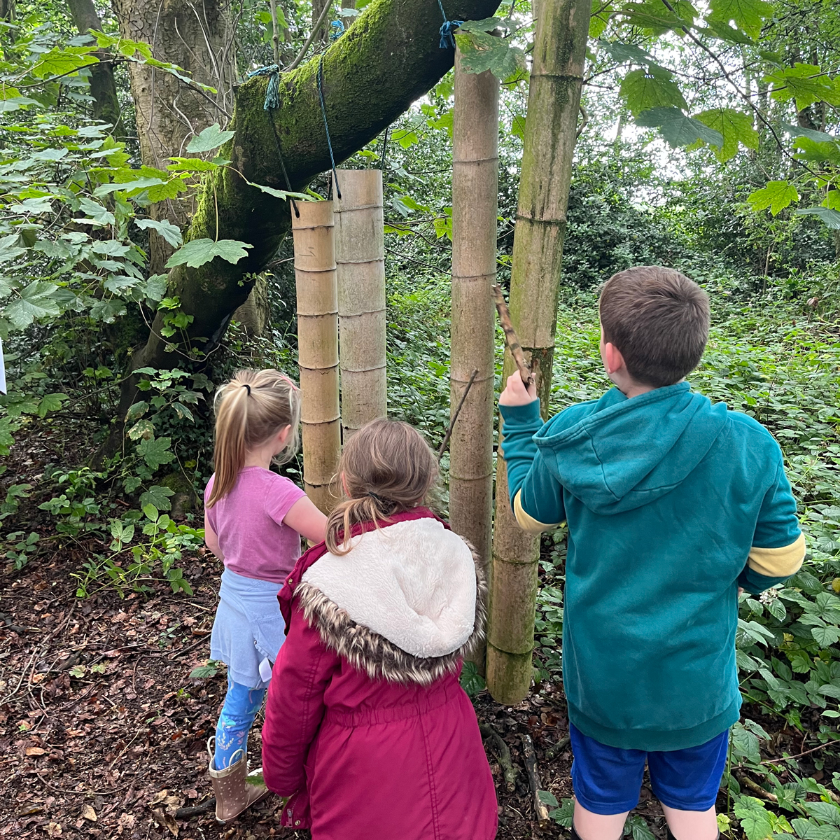 Photo of children play with hanging bamboo tubes