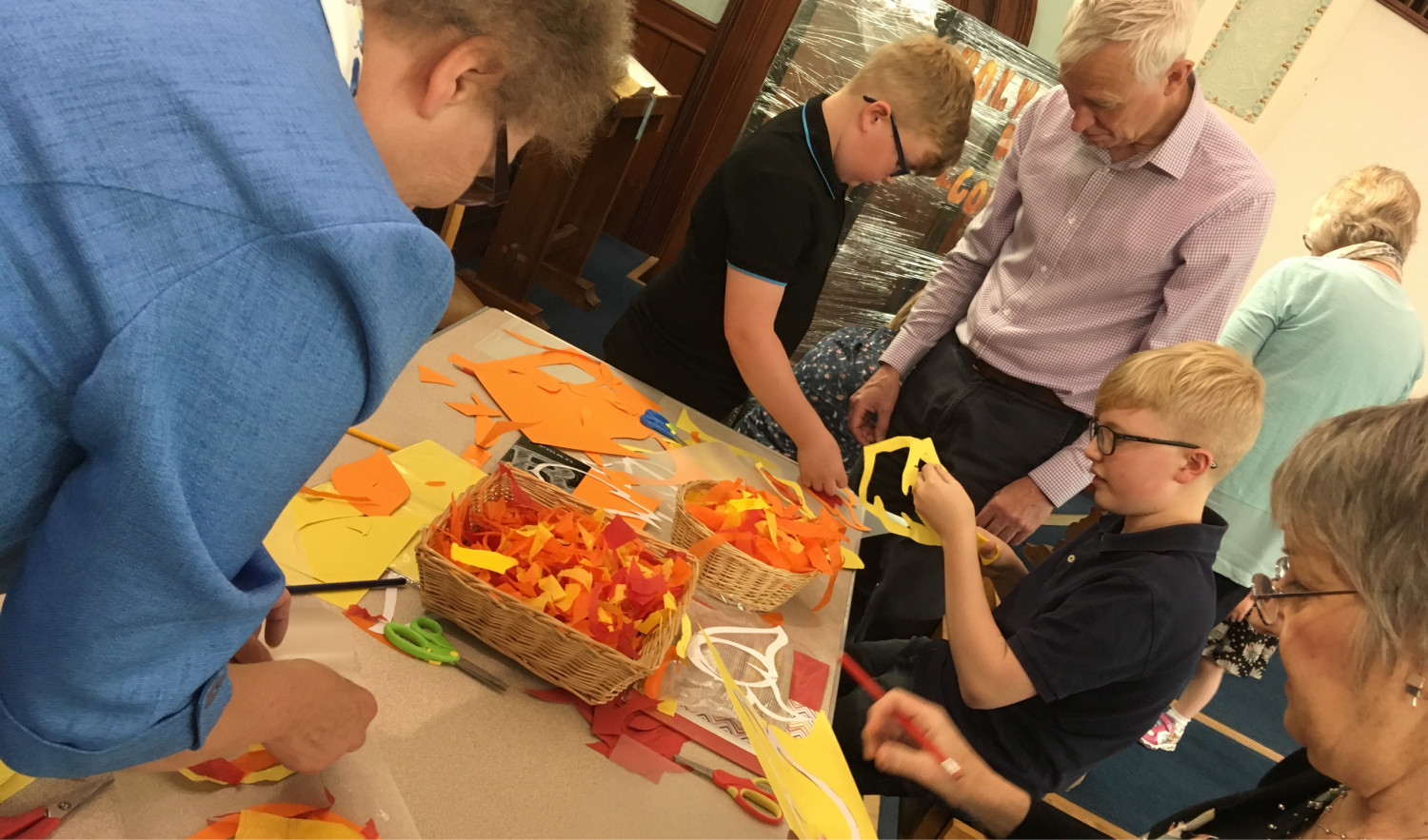 Adults and children engaging in a craft activity around a table